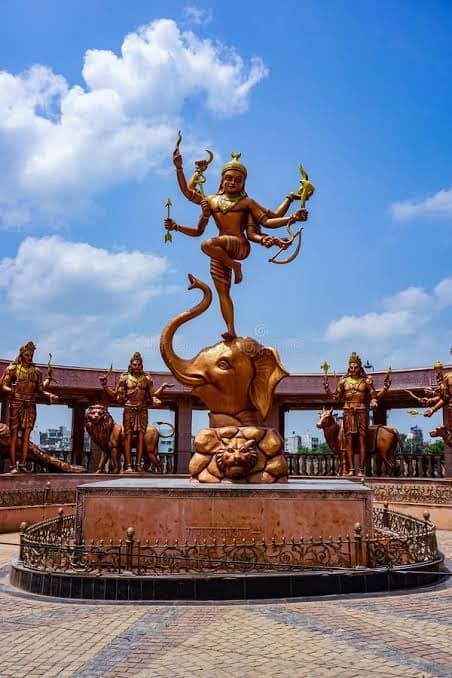 Bronze statues at Mahakal Lok in Ujjain, a dancing Shiva raised above an elephant against a blue sky